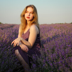 beautiful blonde girl with long hair on a lavender field in the evening - 625567862