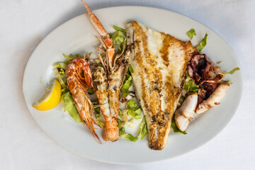 Mix grilled Italian seafood platter consisting shrinps, fish, cuttle fish with salad dressing