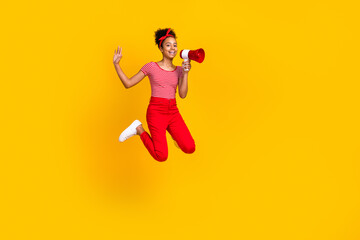 Fototapeta na wymiar Full length photo of cute teen girl jump hold loudspeaker announce wear trendy red striped garment isolated on yellow color background