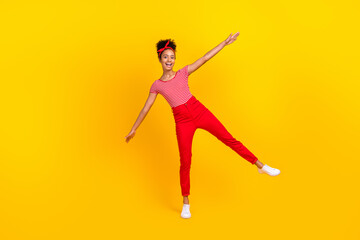 Fototapeta na wymiar Full length photo of cute teen girl spread hands plane wings fooling wear trendy red striped garment isolated on yellow color background
