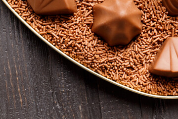 Candies with chocolate praline in chocolate chips on a dark wooden background.