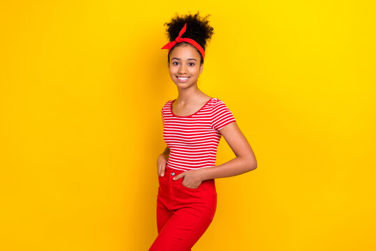 Photo of cute cheerful girl dressed red striped t-shirt smiling hands arms pockets isolated yellow color background