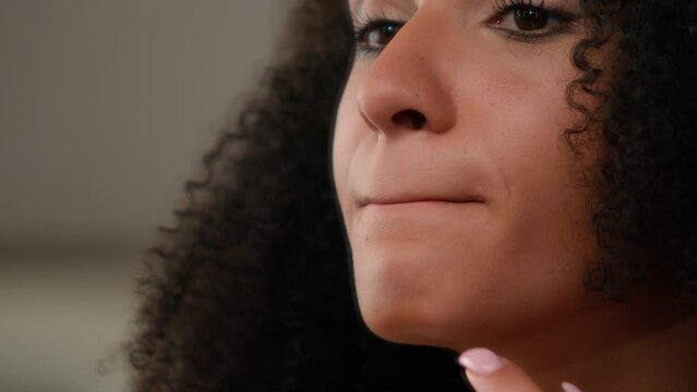 Beautiful young African American woman ethnic girl in bathroom looking in mirror reflection applying moisturizing lip balm hydration lipstick skin care smooth lips organic oil natural cosmetic at home