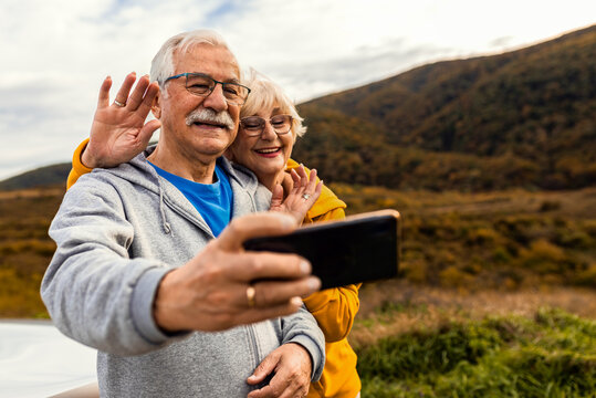 Senior couple esting after hiking in countryside making selfie with smartphone.