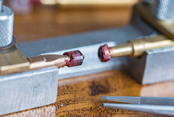 Transferring process from one to another metal dop of the red garnet stone during gems stone cutting process of the crown
