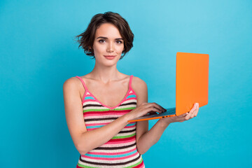 Photo of young confident student woman studying online girl college holding orange laptop texting isolated on blue color background