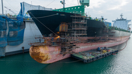 Cargo container ship at dry dock concept maintenance service working in the sea. Insurance and...