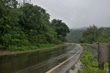 Panoramic landscape view of beautiful wet winding road of Tamhini ghat. Located in Pune, Maharashtra, India, it is surrounded by lush green scenery
