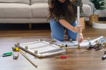 Asian Woman self repairs furniture renovation using equipment to diy repairing furniture sitting on the floor at home