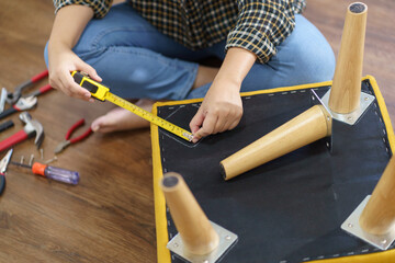 Asian Woman self repairs furniture renovation using equipment to diy repairing furniture sitting on the floor at home