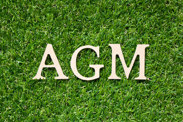 Wood alphabet letter in word AGM (Abbreviation of annual general meeting) on artificial green grass...