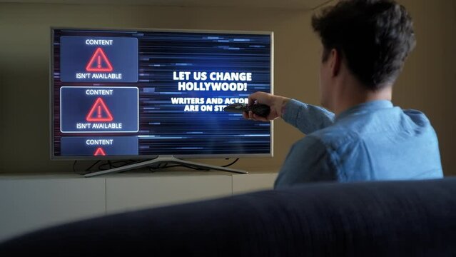 Man emotionally reacts on Hollywood Writers Actors Strike Warning on TV screen
