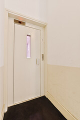 an empty room with white walls and black carpet on the floor, there is a closed door in the corner