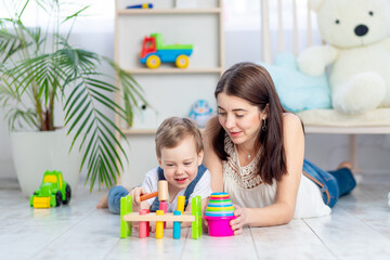 mom plays with the child at home in the educational toys in the children's room. A happy, loving...