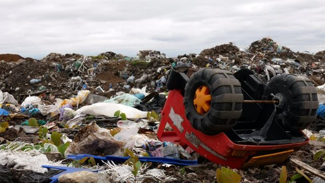 A children's toy lies on the background of a huge pile of household waste. Static filming at the site of the release of unsorted garbage.