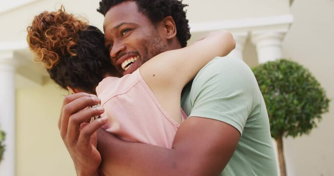 Happy biracial couple embracing with joy in front of new house