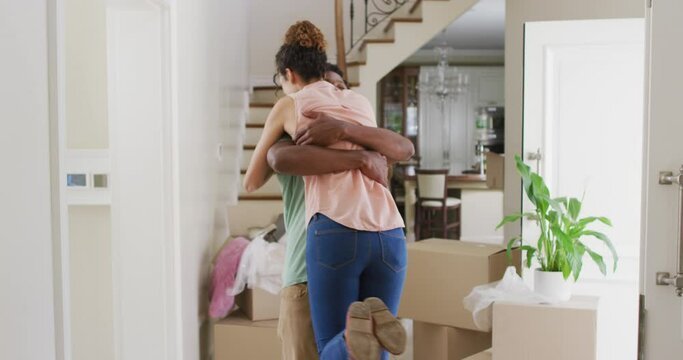 Happy biracial couple hugging with joy in new house