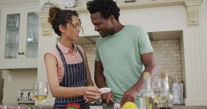 Happy biracial couple cooking together, cutting vegetables