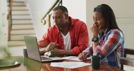 Stressed biracial couple sitting at table with laptop and counting home budget - Powered by Adobe