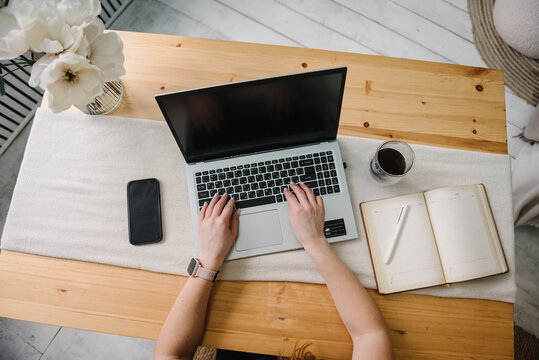 Woman hands working, learns, using laptop computer on table. Writing, typing. Mockup image blank screen, cell phone. Freelance concept. Work home. Online education. Technology concept. Top view.