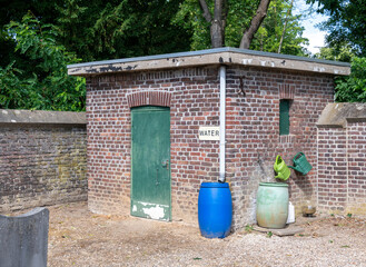Wasserstelle mit Gießkannen auf einem alten Friedhof in Roermond