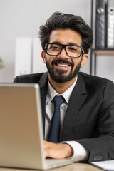 Close-up portrait indian bearded businessman face freelancer at home office workplace working on laptop computer. Manager freelancer indian man works on notebook send messages makes online purchases