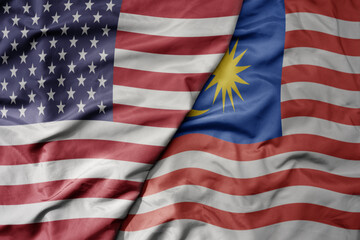 big waving colorful flag of united states of america and national flag of malaysia .