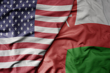 big waving colorful flag of united states of america and national flag of oman .