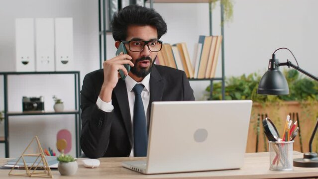 Oh my God, Wow. Happy amazed young indian businessman working on laptop shocked by sudden victory, game winning, lottery goal achievemen, good news. Bearded manager man freelancer at home office