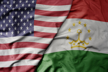 big waving colorful flag of united states of america and national flag of tajikistan .