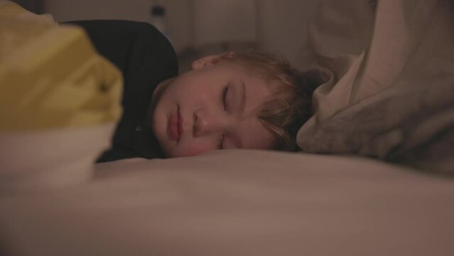 Portrait of a little blond boy sleeping on a bed