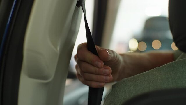 Closeup rear view of unrecognizable driver male pulling seatbelt and buckling himself in before starts driving. Young man fastening car safety seat belt. Car sharing concept, vehicle and transport.