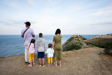 Family of five standing on the top of the mountain looking at the sea. Cape Emine, Black sea coast, Bulgaria.
