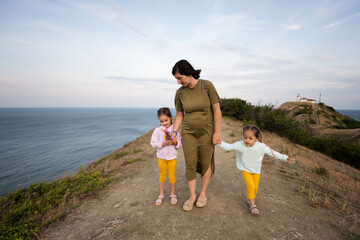 Mother and her two daughters walking on a mountain path by the sea. Cape Emine, Black sea coast, Bulgaria.