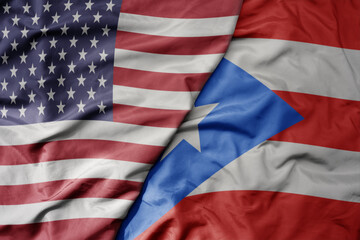 big waving colorful flag of united states of america and national flag of puerto rico .