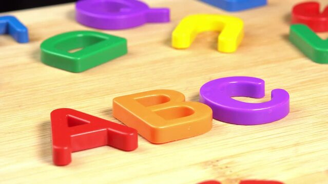 Colorful ABC Alphabet letters rotate on a wooden background. The concept of learning, school or college and knowledge. Plastic English letters, Latin