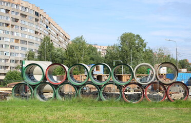 Large diameter pipes are stacked behind a mesh fence, Comrade Avenue, Saint Petersburg, Russia,...