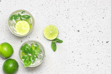 Fresh iced lemonade with lime and basil on light marble table top view, copy space for your design. Refreshing summer drink.