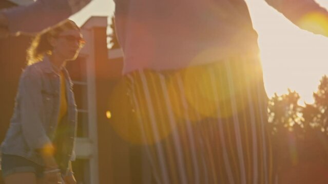 Tilt shot of three female teenagers wearing colorful outfits riding on roller skates outside at daytime