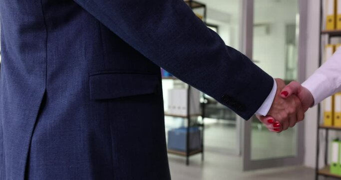 Businessman shakes hands of partner at meeting in company office slow motion. Colleague greets female employee with handshake gesture