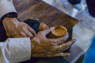 Tea in a clay pot is held by hand for drinking. Traditional way of serving the popular beverage in...