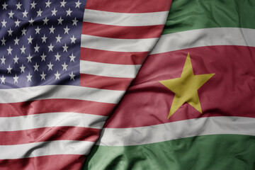 big waving colorful flag of united states of america and national flag of suriname .