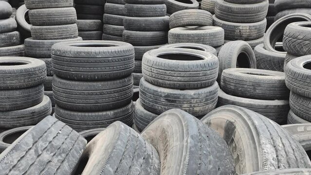 A large pile of old used tires in an auto repair shop where customers come in to replace their faulty tires. concept of recycling used tires or making good use of old tires.