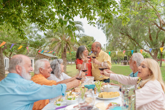 Mature couple celebrating anniversary in park with friends