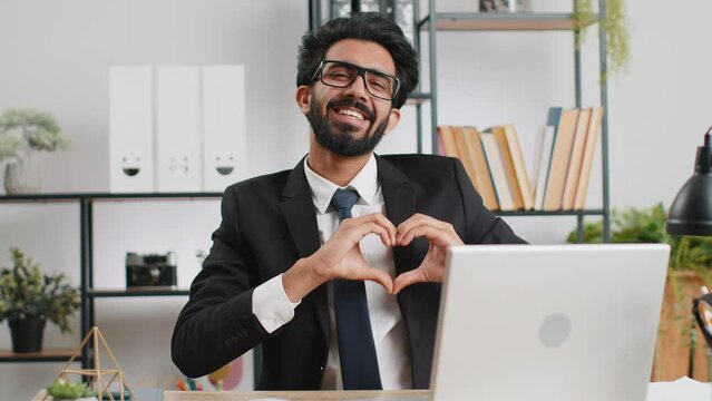 I love you. Indian business man makes symbol of love, showing heart sign to camera, express romantic feelings, express sincere positive feelings at home office workplace. Charity, gratitude, donation