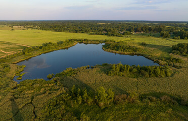 Pond in countryside, aerial view. Small lake in agricultural field near forest. Rural landscape. Wet, wild Pond with clean water. Wildlife Refuge Wetland Restoration, groundwater. Green Nature.