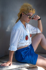 Italian girl cosplay Giorno Giovanna from the anime jojo. Blond woman with blue eyes. Close up to the sea and greenery.