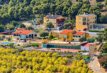 Fototapeta premium Rural landscape, aerial view. Villa in mountains. Farmhouse with garden field. Houses at mountain in countryside. House in farm field. Mountains landscape with farmland. Village Home in mountains.