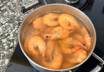 Cooking shrimp on stove in kitchen. Shrimp boiled in a pot on fire. Prepared shrimp in restaurant. ...