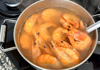 Cooking shrimp on stove in kitchen. Shrimp boiled in a pot on fire. Prepared shrimp in restaurant.  Orange red tiger prawns. Sea food prawn background. Mediterranean food. Seafood tiger shrimp